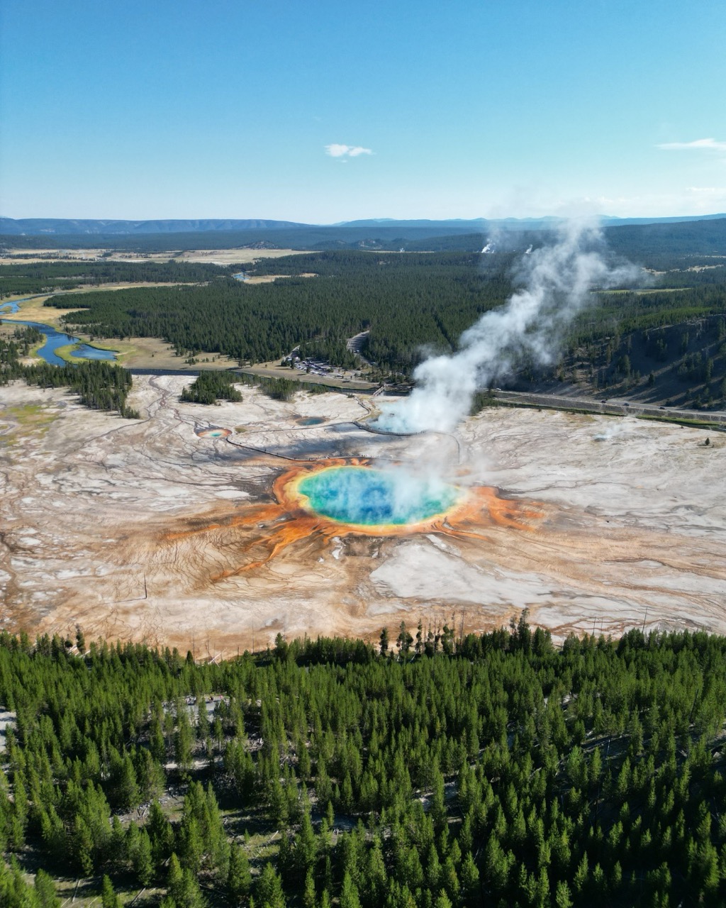 Aerial view of Grand Prismatic Spring surrounded by forest