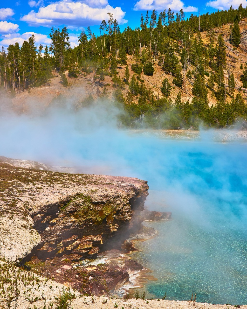 Steaming turquoise hot spring with a mineral terrace
