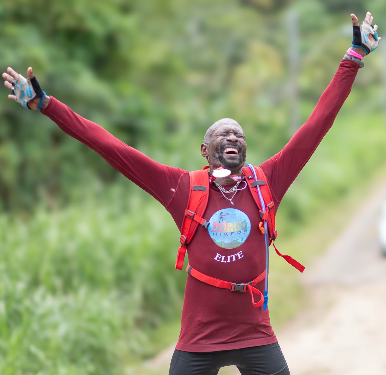 A hiker in red celebrating with both arms up