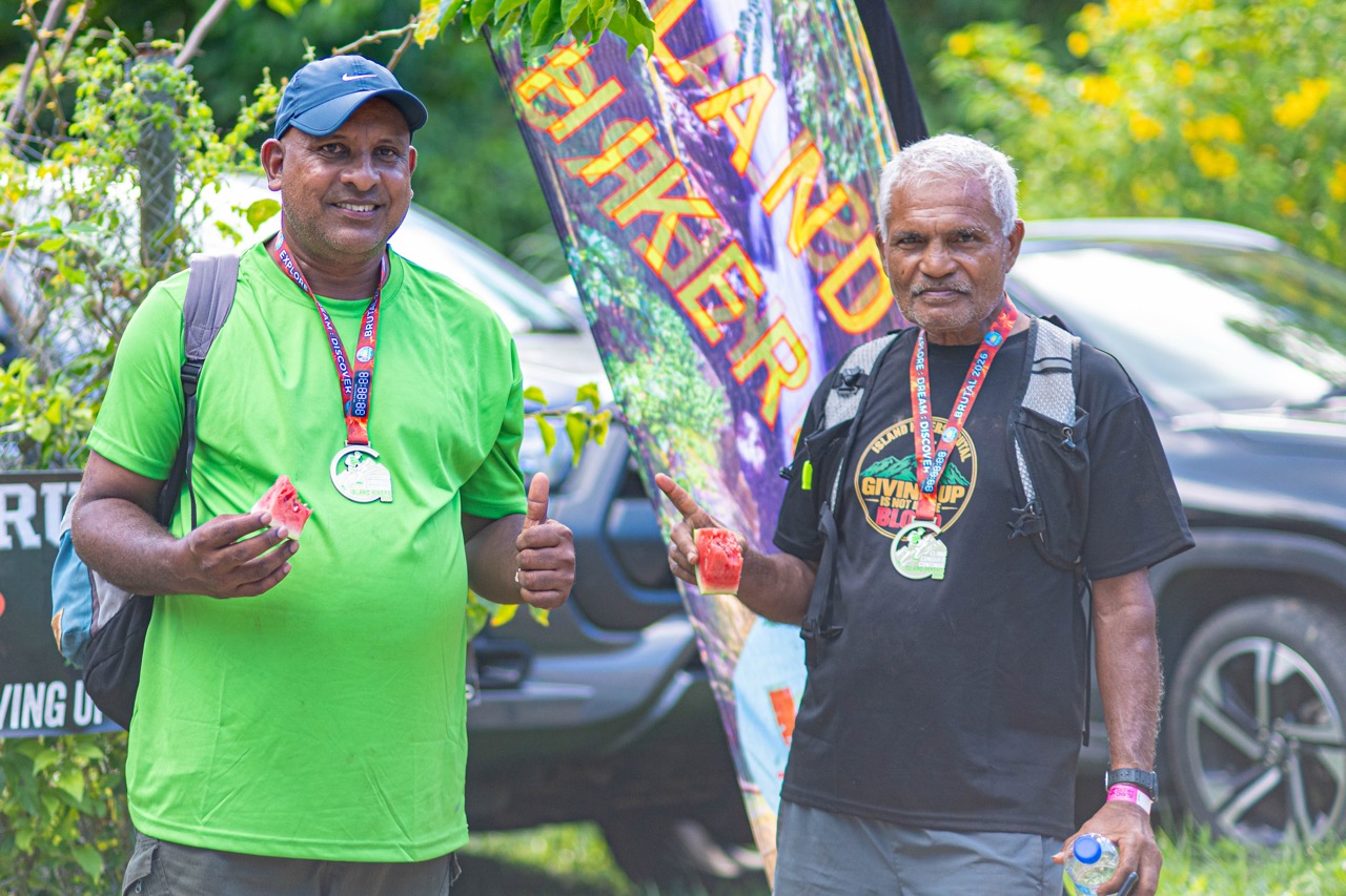 Two finishers with medals eating watermelon